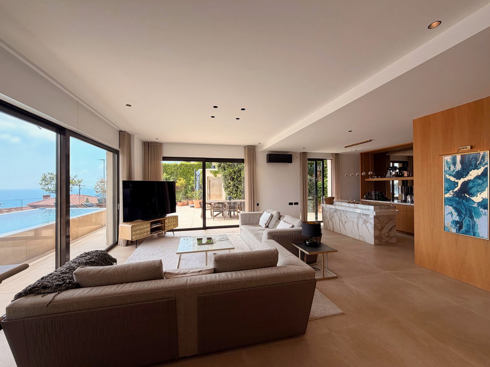 Salon ouvert avec baies vitrées sur la terrasse, la piscine et la mer